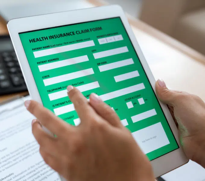 Person filling out a digital insurance claim form on a tablet